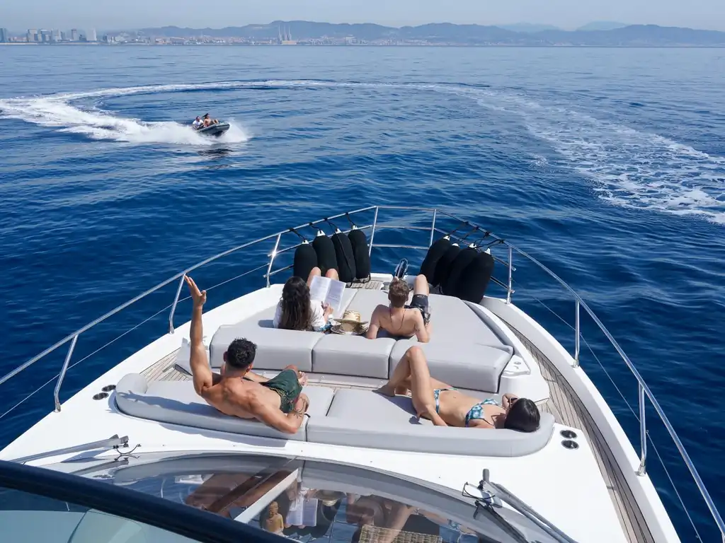 Pasajeros tomando el sol en la proa del yate Azimut 53 con la costa al fondo