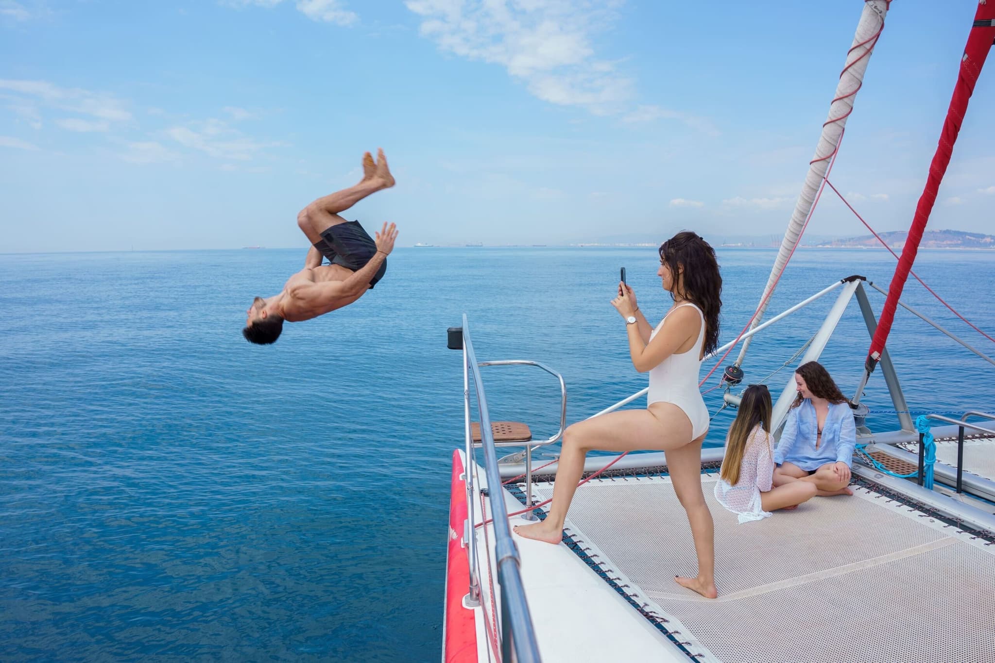 Hombre haciendo un salto mortal al mar desde el catamarán mientras le graban